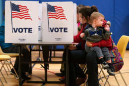 ALEXANDRIA, VA - NOVEMBER 07: Karina Smith holds her 2-year-old son Kyler as she fills out her ballot at the polling place at Washington Mill Elementary School November 7, 2017 in Alexandria, Virginia. (Photo by Chip Somodevilla/Getty Images)