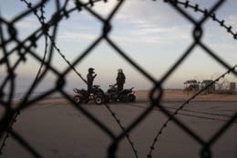 Two U.S. Border Patrol agents talk along the beach in San Diego, Wednesday, Jan. 9, 2019, seen through razor wire lining the border wall from Tijuana, Mexico. U.S. President Donald Trump walked out of his negotiating meeting with congressional leaders Wednesday — "I said bye-bye," he tweeted— as efforts to end the 19-day partial government shutdown fell into deeper disarray over his demand for billions of dollars to build a wall on the U.S.-Mexico border. (AP Photo/Gregory Bull)