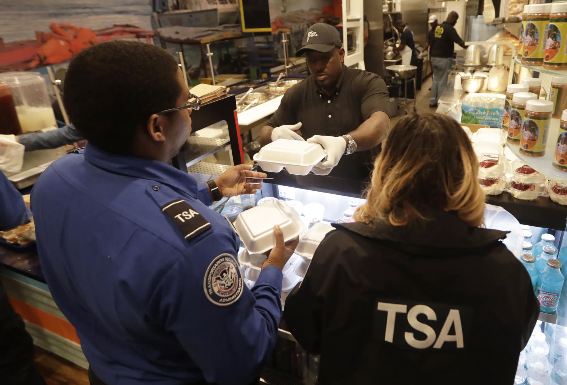 Chef Creole owner Wilkinson Sejour hands out free hot meals to TSA workers at his restaurant at Miami International Airport, Tuesday, Jan. 15, 2019, in Miami. The restaurant is offering free lunch and dinner to federal airport employees affected by the government shutdown. (AP Photo/Lynne Sladky)